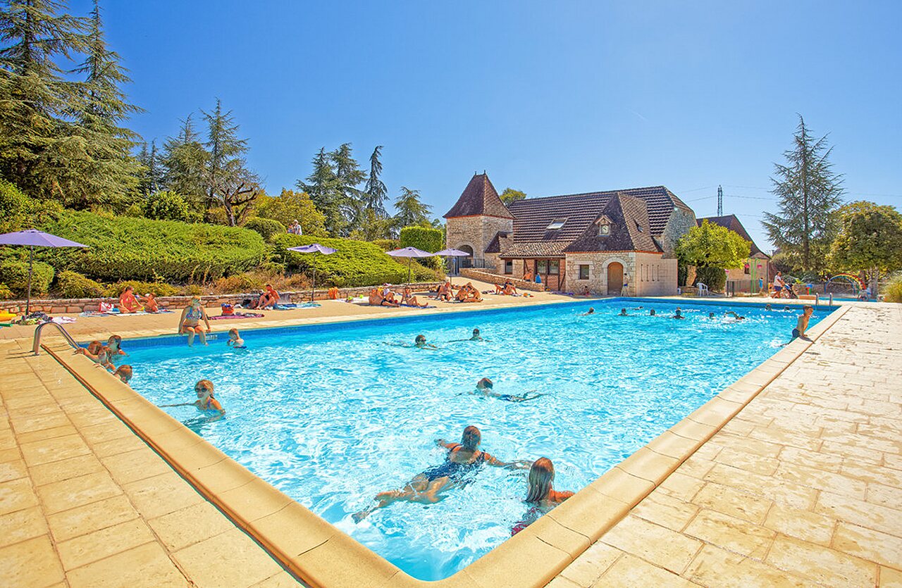 Outdoor pool, swimmers, traditional building, VAGUES OCEANES Paille Basse campsite in Souillac (46).