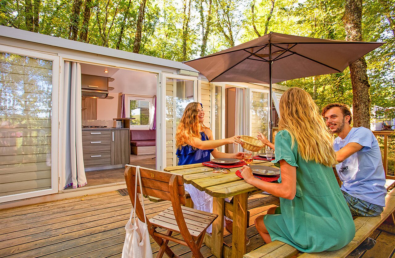 Modern mobile home, wooden terrace, family meal at VAGUES OCEANES Paille Basse campsite.