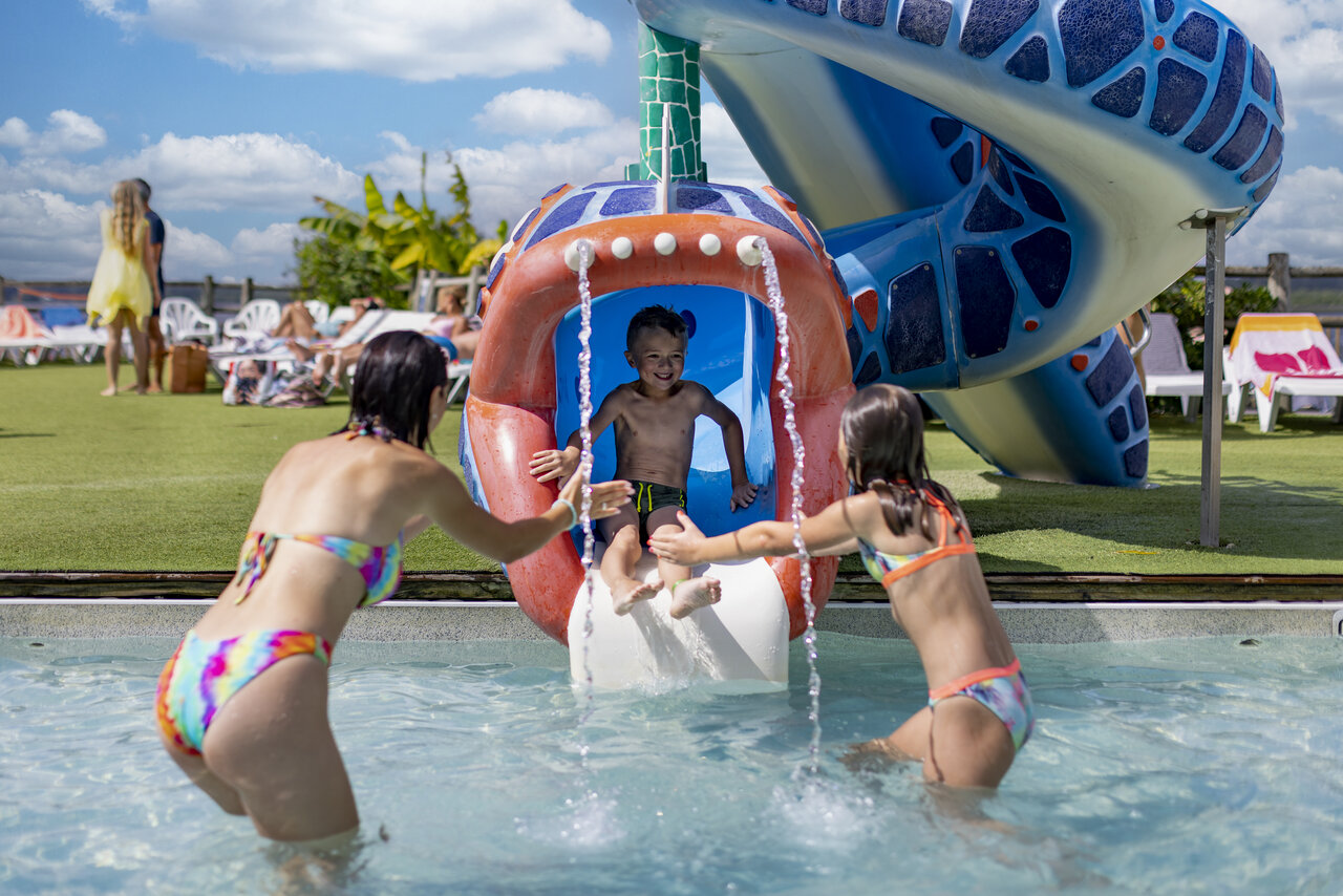 Child sliding down water slide in pool at CAPFUN Paillotte campsite in AZUR (40).