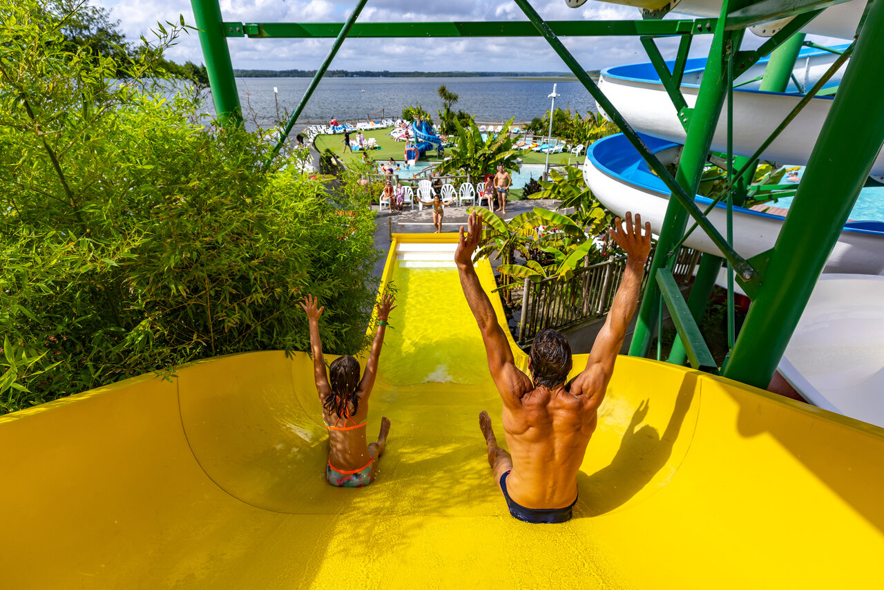 Yellow water slide, man and child, pool, lake at CAPFUN Paillotte campsite AZUR (40).