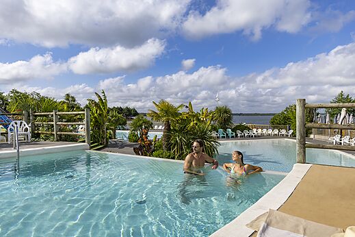 Outdoor swimming pool with adults relaxing at CAPFUN Paillotte campsite in AZUR (40).