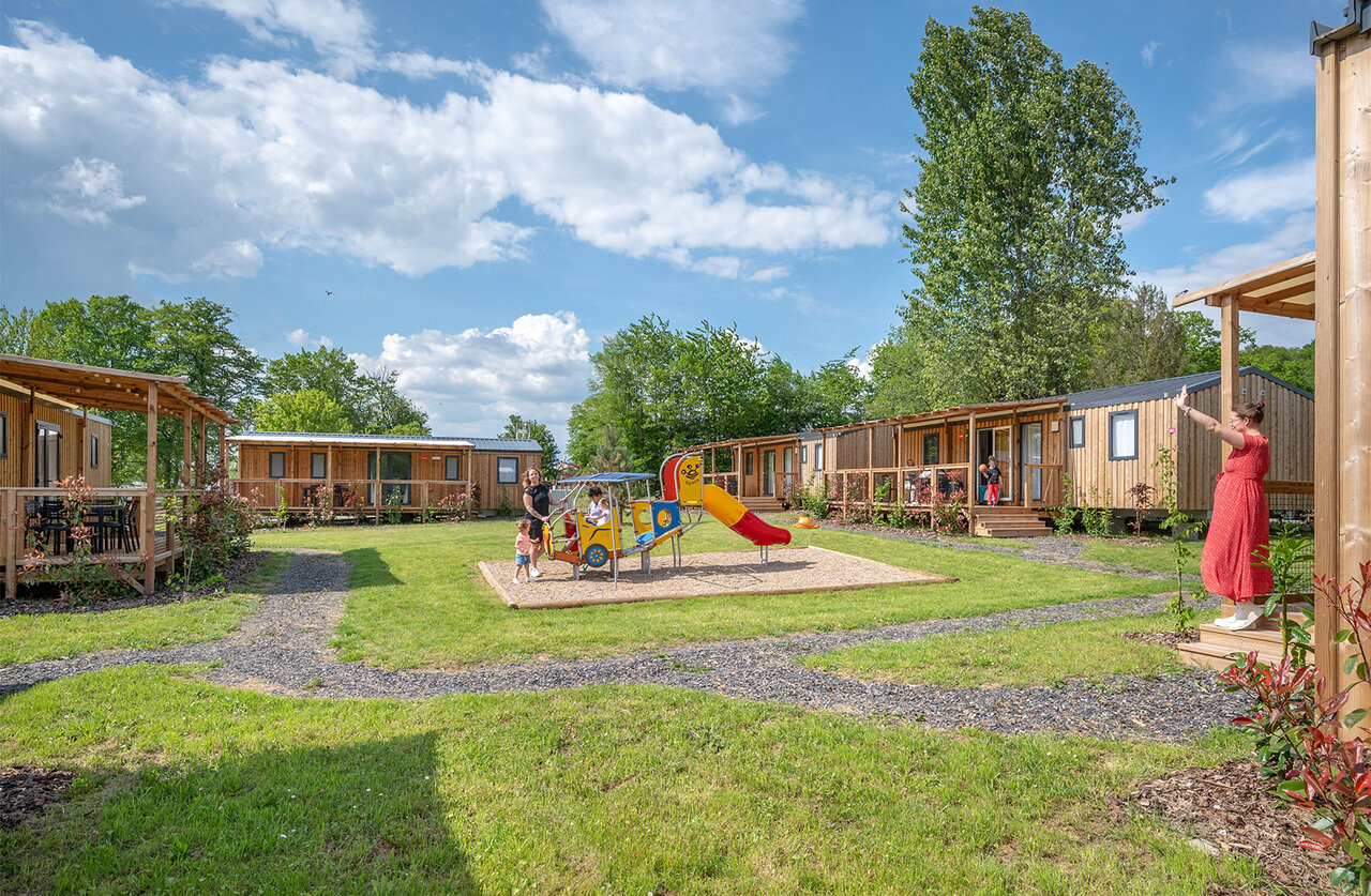 Wooden mobile homes and playground at CAPFUN Palais de Gaufrette campsite.