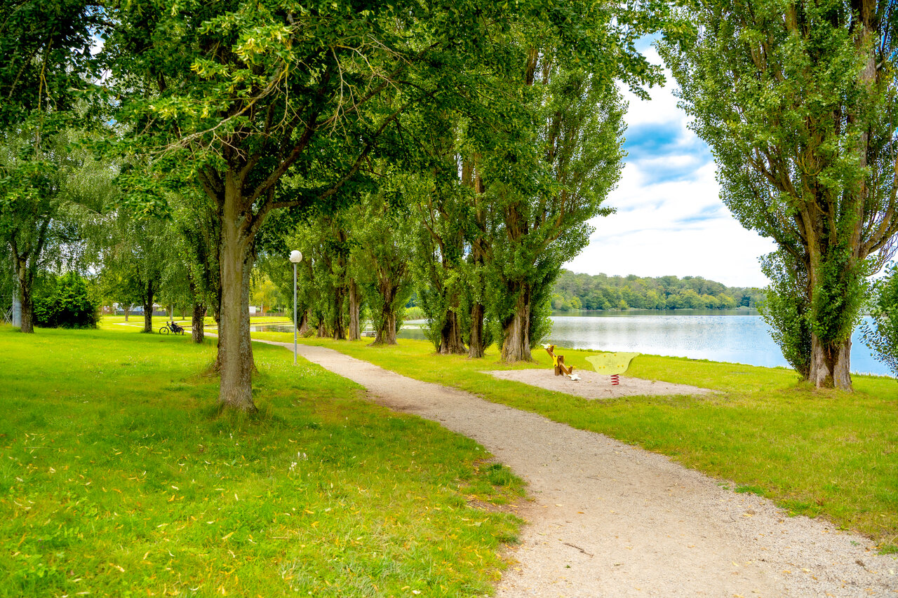 Green path along the lake with children's playground at CAPFUN Palais de Gaufrette campsite in R�mering les Puttelange (57).
