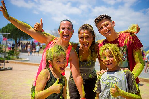 Smiling family covered in colored powder during an activity at CAPFUN Palombi�re campsite in SAINT-NATHALENE.
