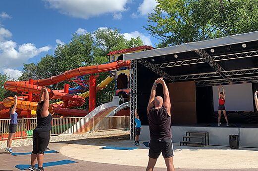 Outdoor fitness class with water slides at CAPFUN Palombi�re campsite in SAINT-NATHALENE.