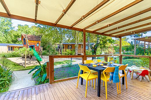 Covered terrace with dining table and playground at CAPFUN Paradis de Bazas campsite in BAZAS (33).
