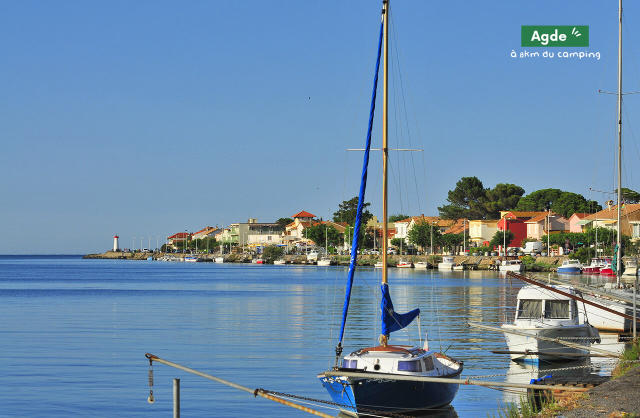 Agde harbor with boats, colorful houses and lighthouse, near the campsite.