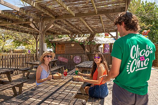Shaded outdoor bar, picnic tables at CLICOCHIC Paradou campsite in Marseillan-Plage.