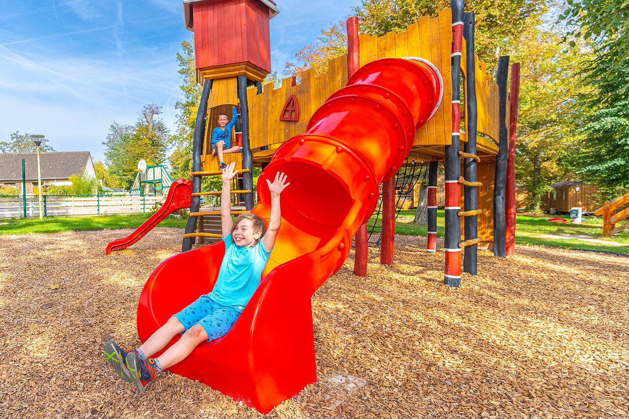 Smiling child on red slide playground at CAPFUN Parc de Paris campsite in Villevaud� (77).