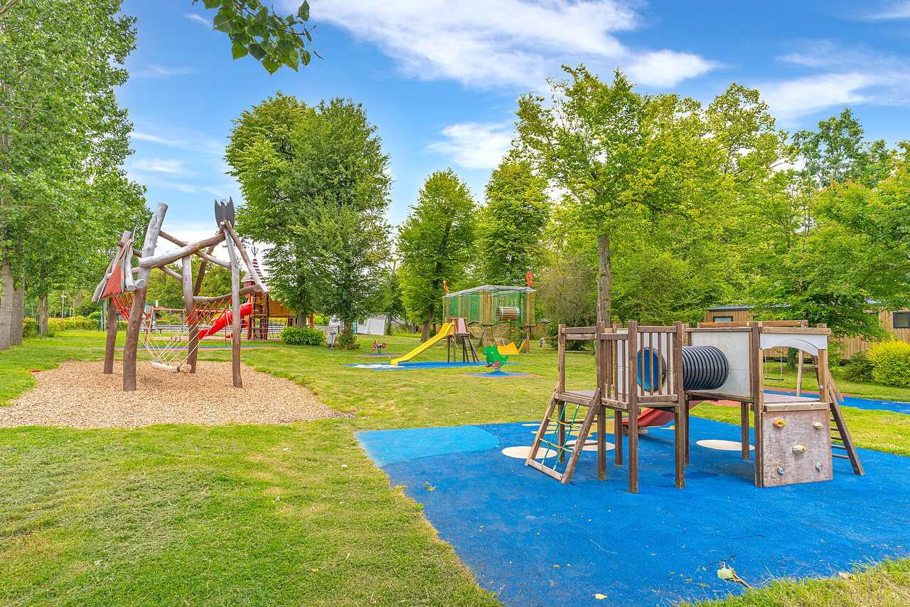 Outdoor playground with slides, wooden structures, and swings at CAPFUN Parc de Paris campsite in Villevaud� (77).