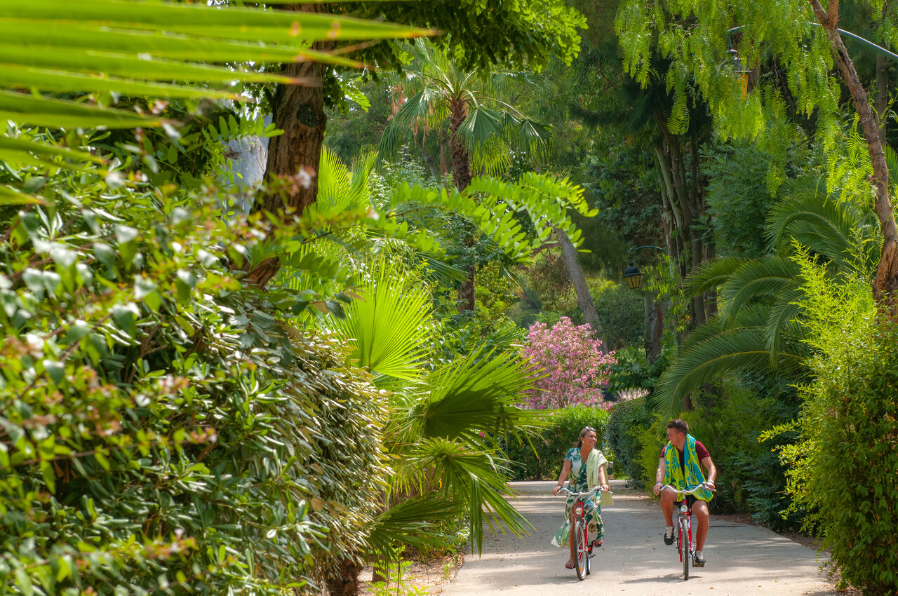 Couple cycling on a green path at CAPFUN Parc et Plage campsite in Hy�res les Palmiers (83).