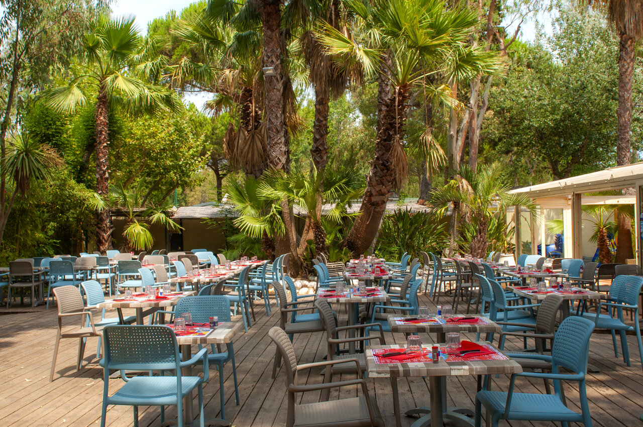 Outdoor restaurant terrace, tables, palm trees, CAPFUN Parc et Plage Hy�res (83).