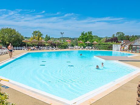Large outdoor pool with chairs and parasols at CAPFUN Pergola campsite in Marigny (39).