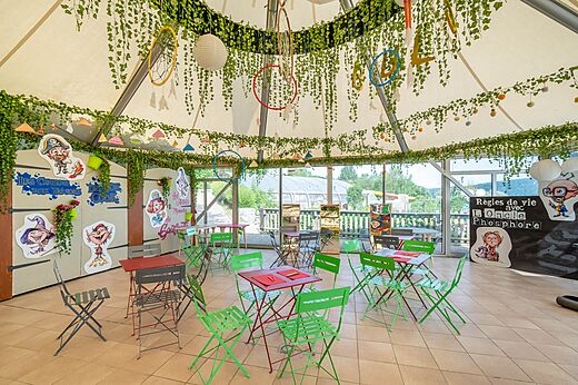 Decorated kids' entertainment room with tables and chairs at CAPFUN Pergola campsite in Marigny (39).
