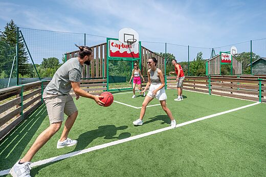 Family playing basketball on the multisport court at CAPFUN Pergola campsite in Marigny (39).