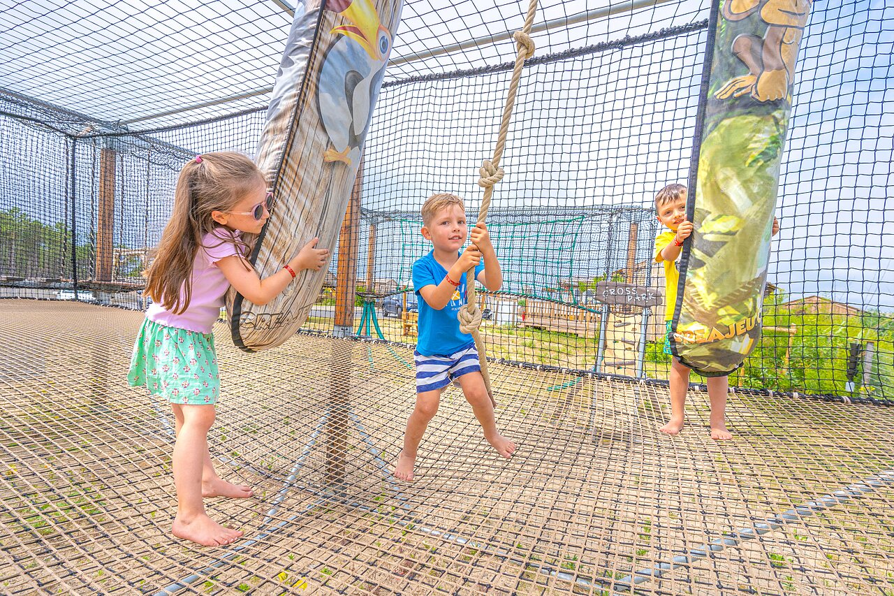 Children playing on a net playground structure at CLICOCHIC Petit Nice campsite in PYLA SUR MER (33).