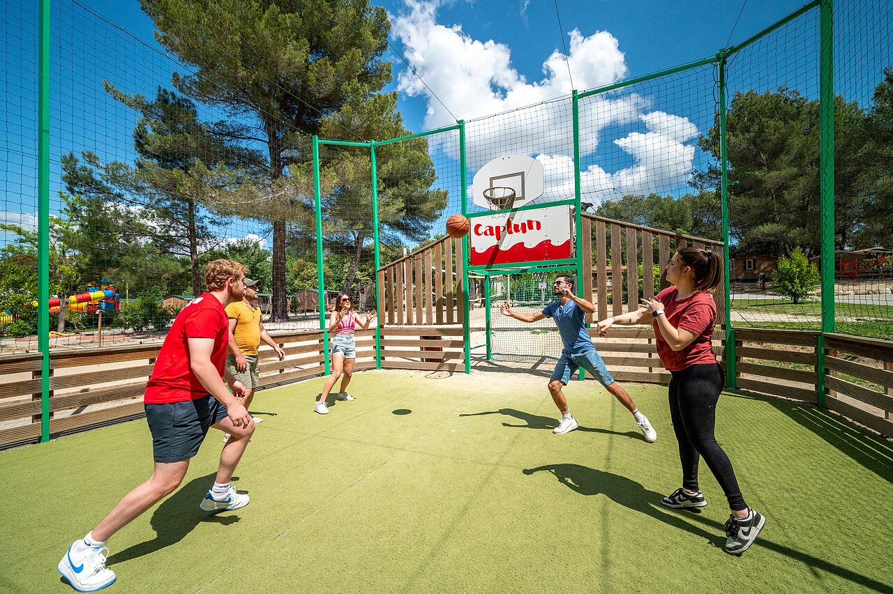 Multi-sports court, friends playing basketball at CAPFUN Pin�des du Luberon campsite.