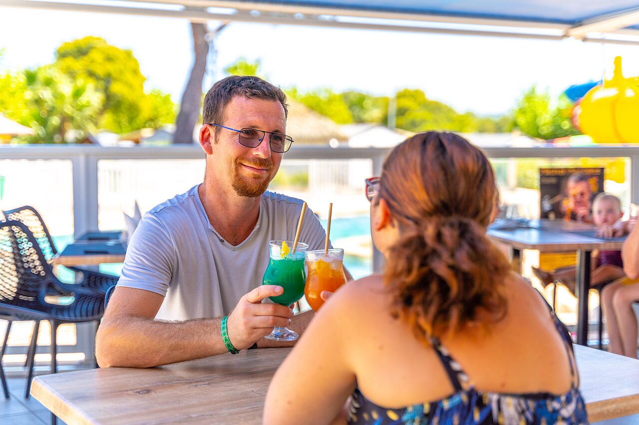 Couple enjoying cocktails at the bar of CAPFUN La Pin�de de Grimaud campsite.