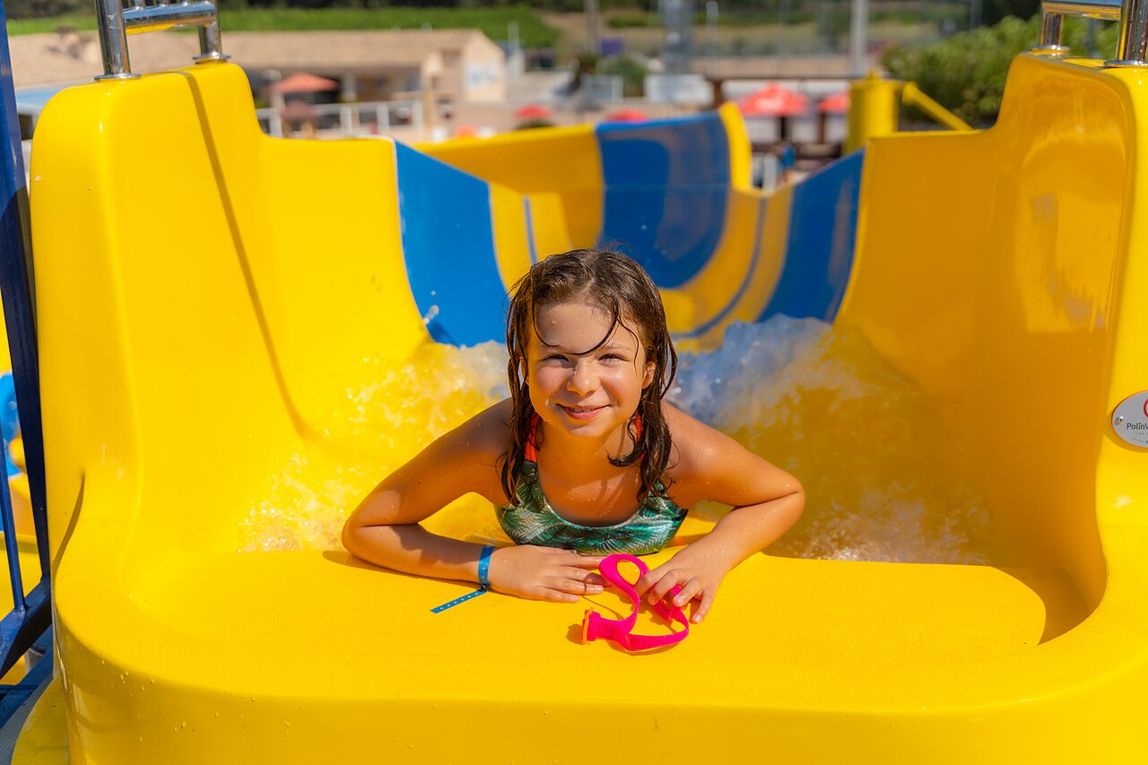 Smiling child on yellow slide at CAPFUN La Pin�de de Grimaud campsite (83).