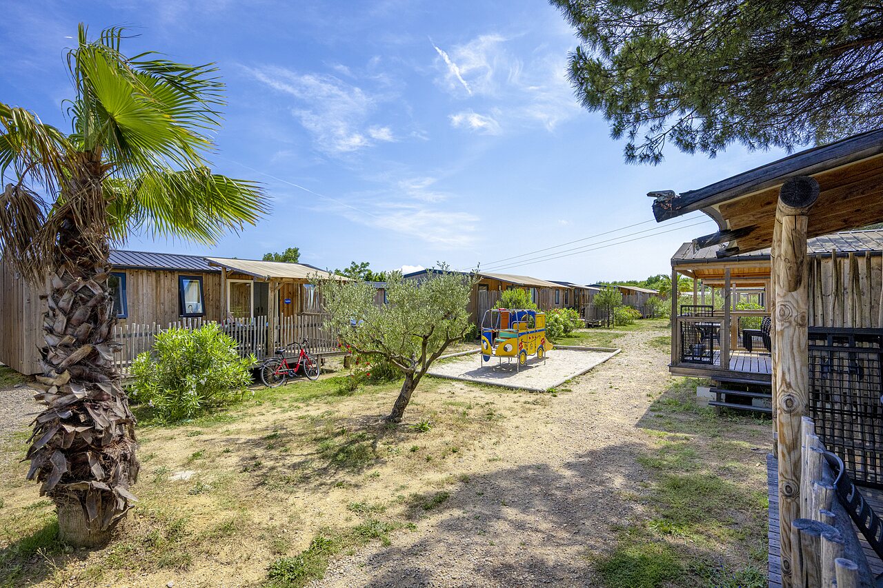Wooden Mobile-homes, playground and palm trees at CAPFUN La Pin�de de Grimaud campsite in Grimaud (83).