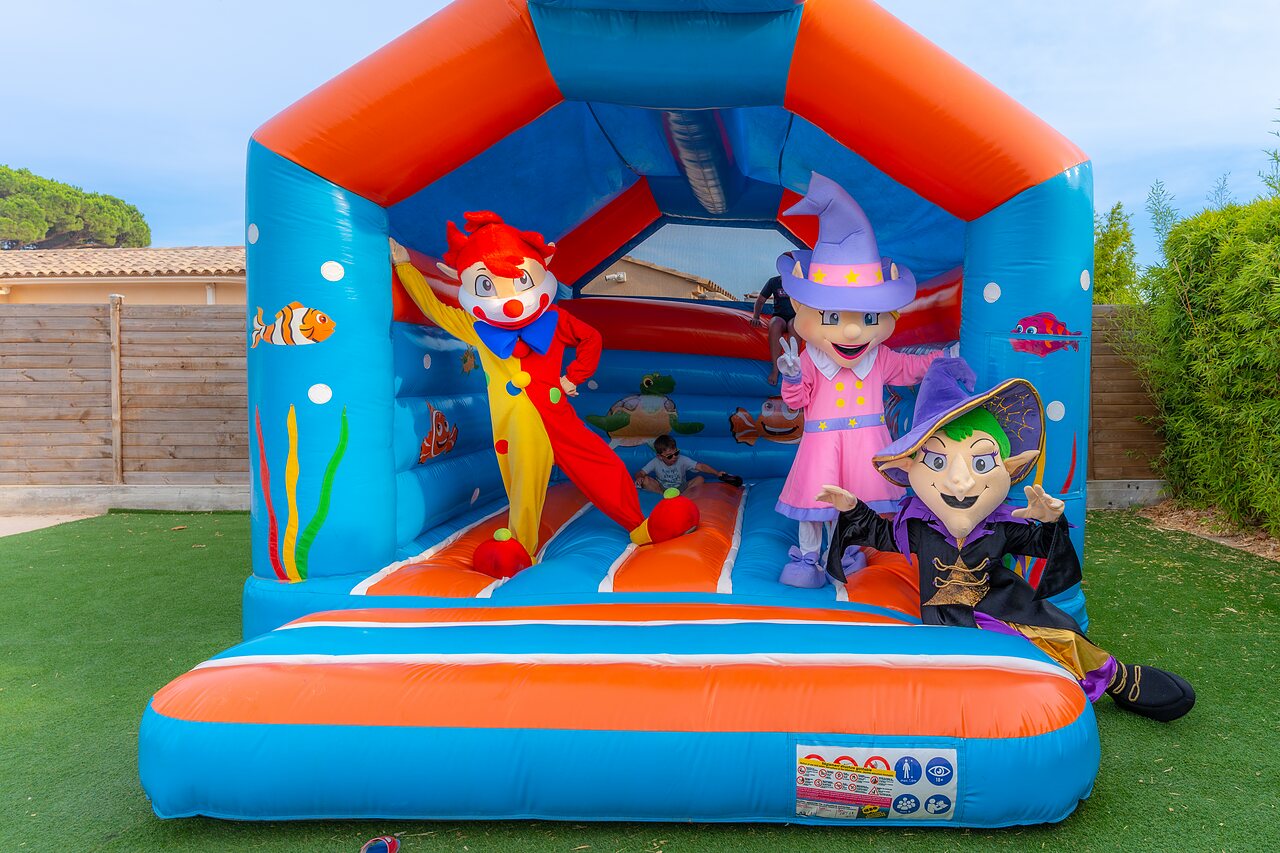 Colorful bouncy castle with mascots and children at CAPFUN La Pin�de de Grimaud campsite in Grimaud (83).