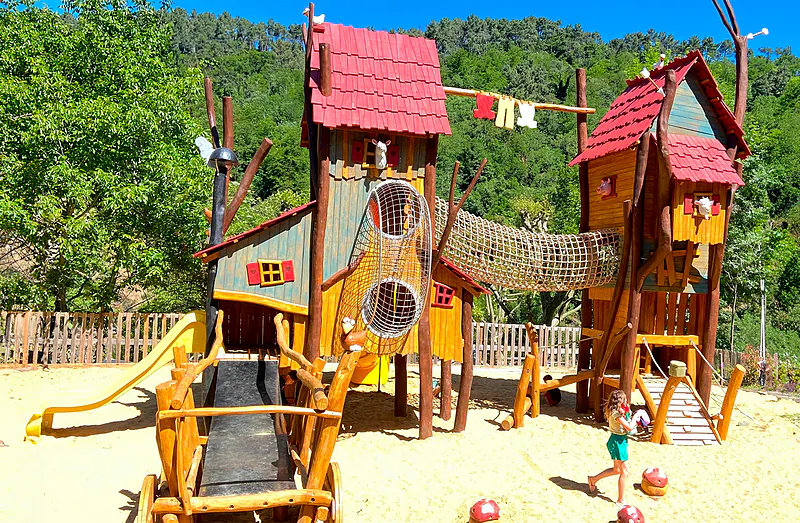 Wooden playground with slides and climbing nets at CAPFUN Plantas campsite in SAINT VINCENT DE DURFORT.