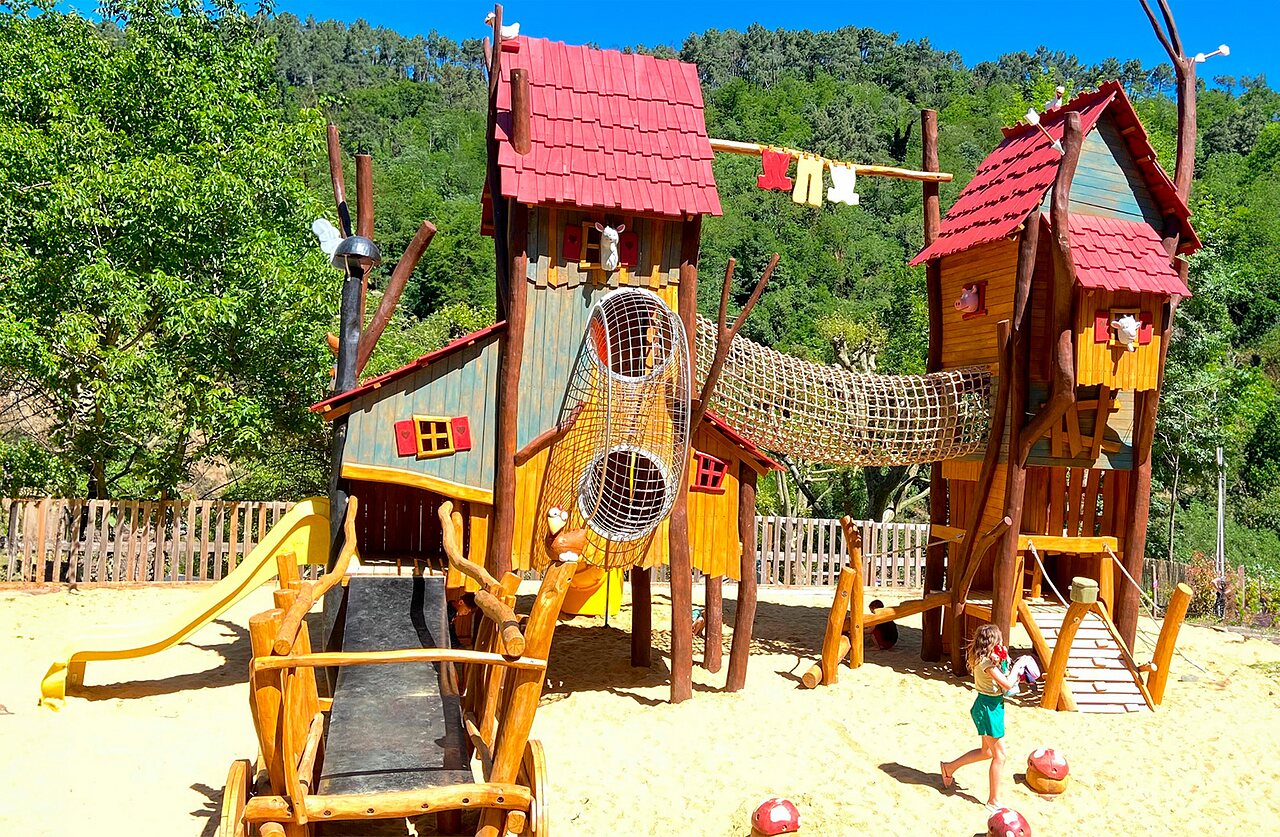 Wooden playground with slides and climbing nets at CAPFUN Plantas campsite in SAINT VINCENT DE DURFORT.