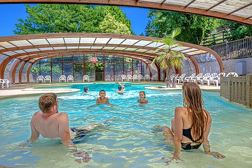 Covered swimming pool with family at CAPFUN Plantas campsite in SAINT VINCENT DE DURFORT (07).