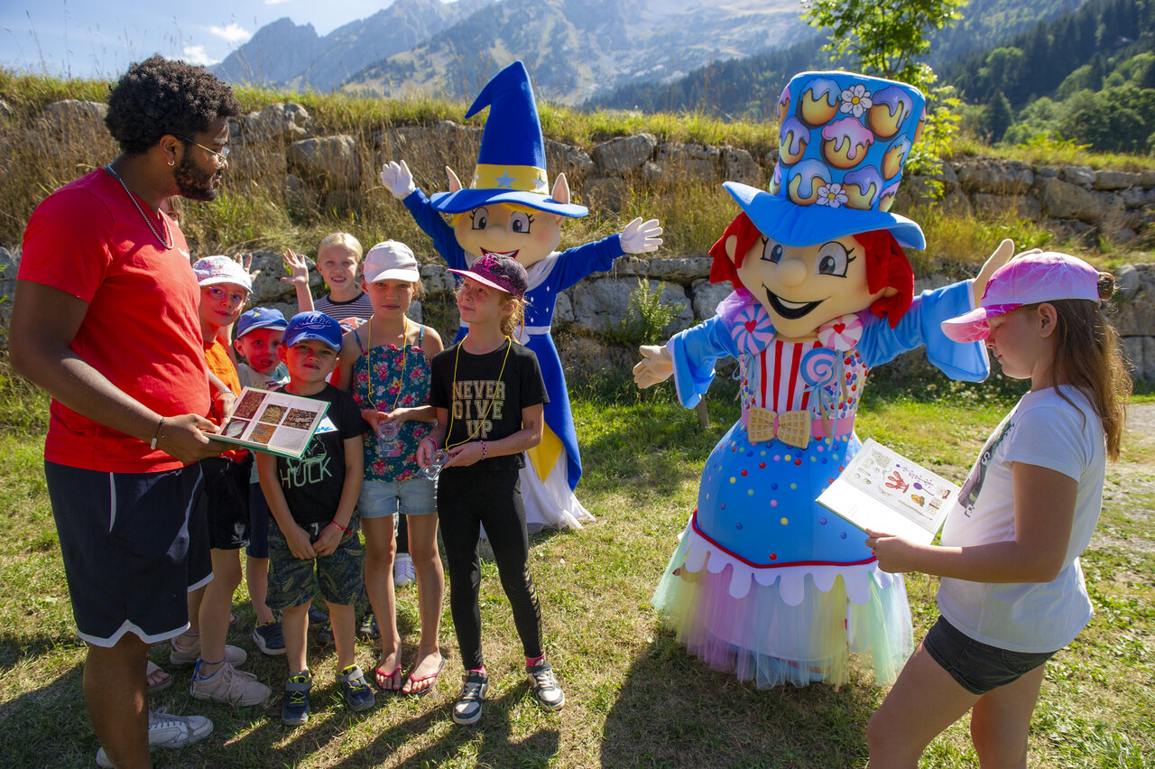 Animator, children and mascots during outdoor activity at CAPFUN Plan du Fernuy campsite in LA CLUSAZ (74).