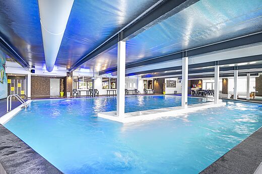 Heated indoor swimming pool with blue lighting at CAPFUN Ponderosa campsite in Ulicoten.