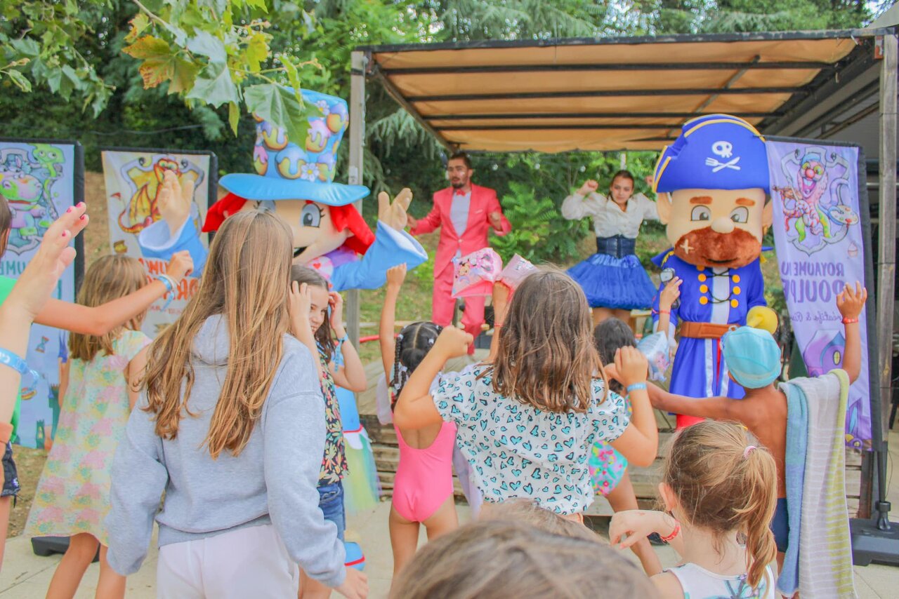 Children dancing with mascots and entertainers on stage at CAPFUN Les Portes du Beaujolais campsite in Anse (69).
