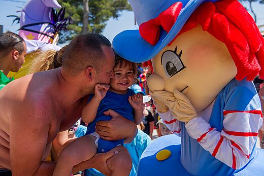 Smiling father and child with animation mascot at CAPFUN Les Portes du Beaujolais campsite in Anse (69).