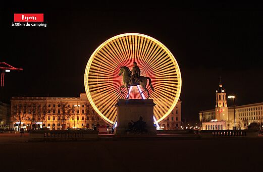 Illuminated Ferris wheel and equestrian statue in Lyon, city to visit in Rh�ne-Alpes.