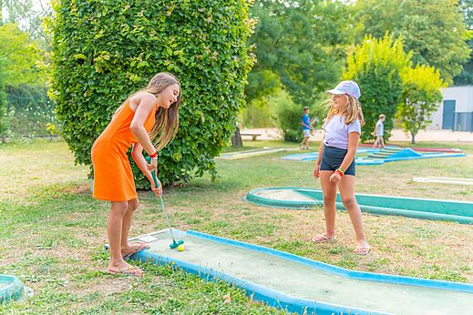 Mini-golf with two young girls playing at CAPFUN Les Portes du Beaujolais campsite in Anse (69).