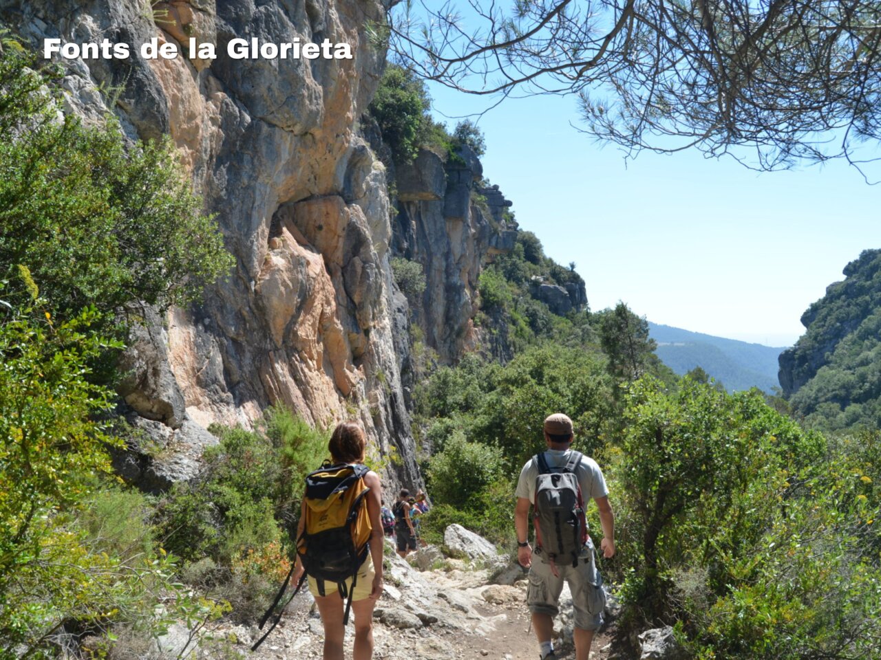 Rocky hiking trail, cliffs, and lush vegetation at Fonts de la Glorieta.