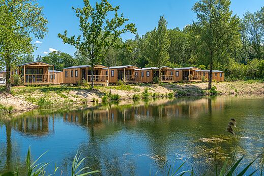 Wooden mobile homes by a pond, at VAGUES OCEANES campsite Pr�s de la Fontaine � Gouaix (77).
