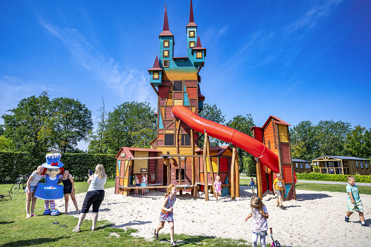 Colorful play castle with slide and children at CAPFUN Rakelbos campsite in Westelbeers.