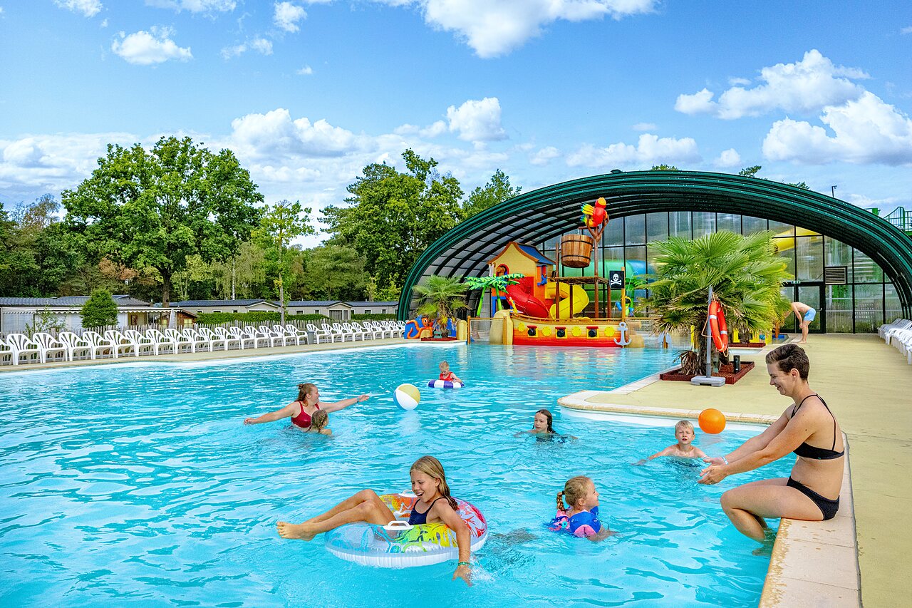 Outdoor swimming pool with water games and families at CAPFUN Rakelbos campsite in Westelbeers.