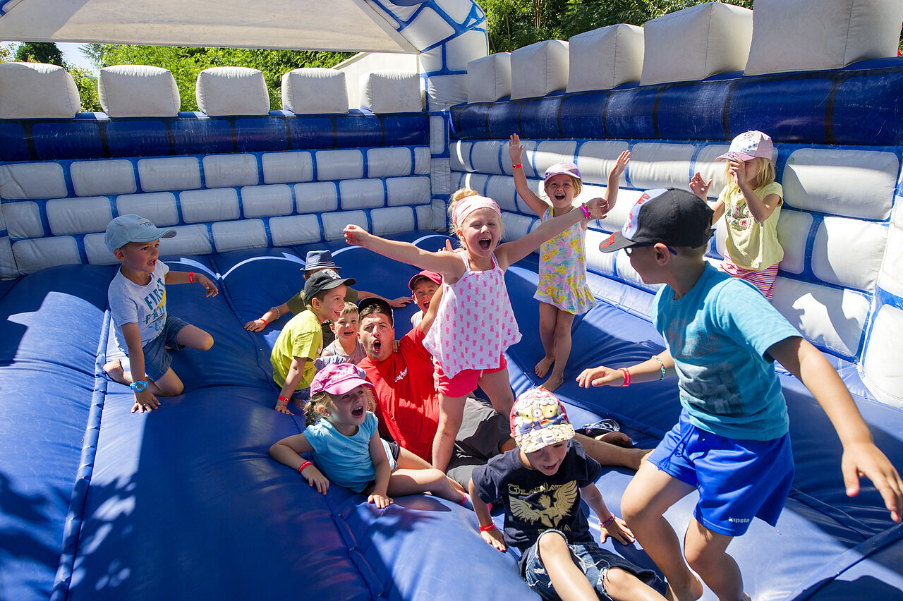 Children and animator having fun on an inflatable castle at CAPFUN Rakelbos campsite in Westelbeers.