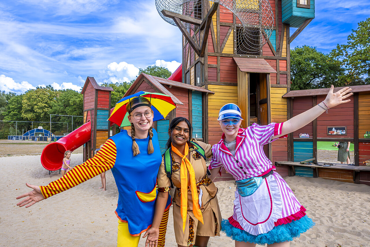 Smiling animators in front of colorful playground with slide at CAPFUN Rakelbos campsite in Westelbeers