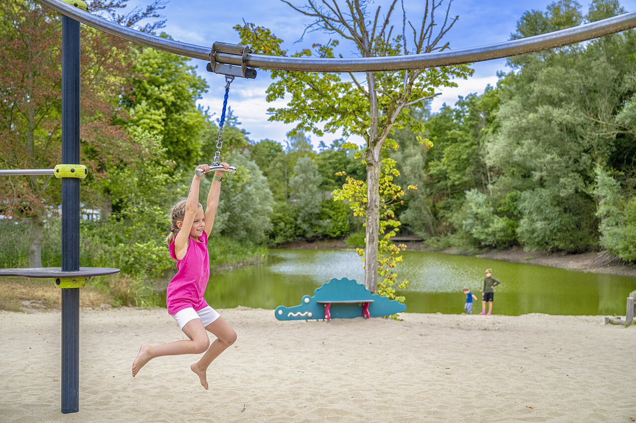 Child on zip line, sandy beach, pond, CAPFUN Rakelbos campsite Westelbeers.