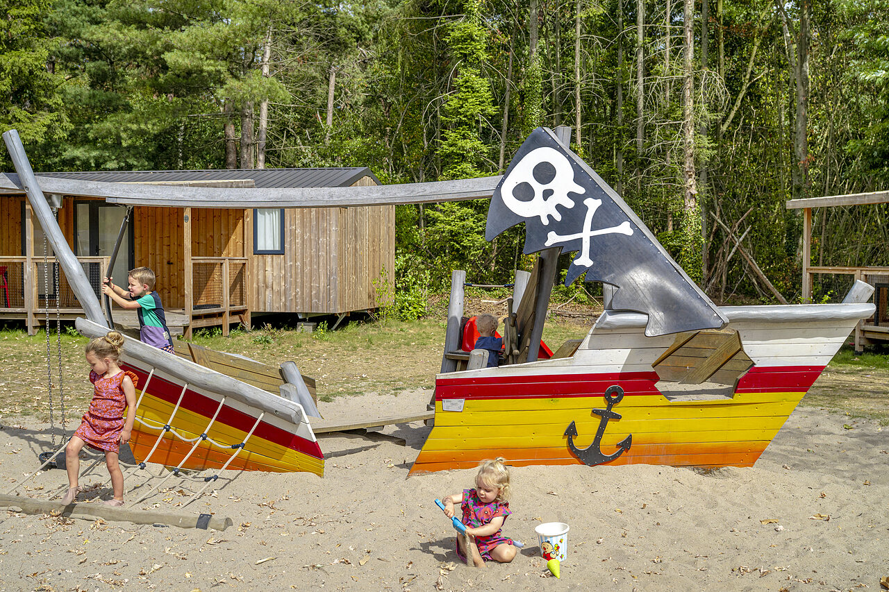 Children playing on pirate ship playground with Mobile homes at CAPFUN Rakelbos campsite in Westelbeers.