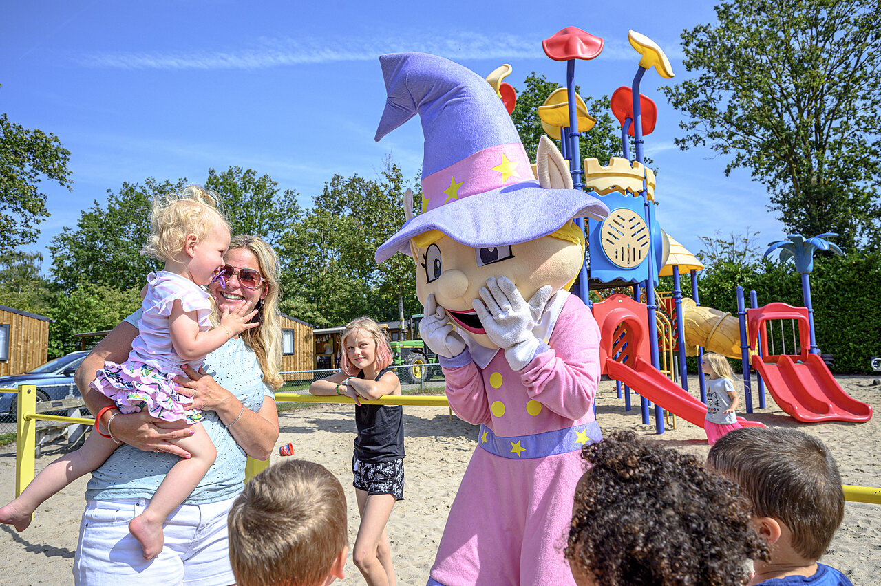 Mascot and smiling children on the playground at CAPFUN Rakelbos campsite in Westelbeers.