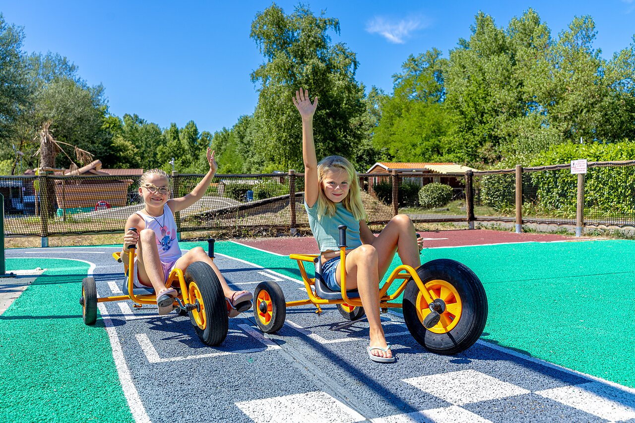 Smiling children on pedal karts, playground CAPFUN R�gni�re VILLETTE D'ANTHON (38).
