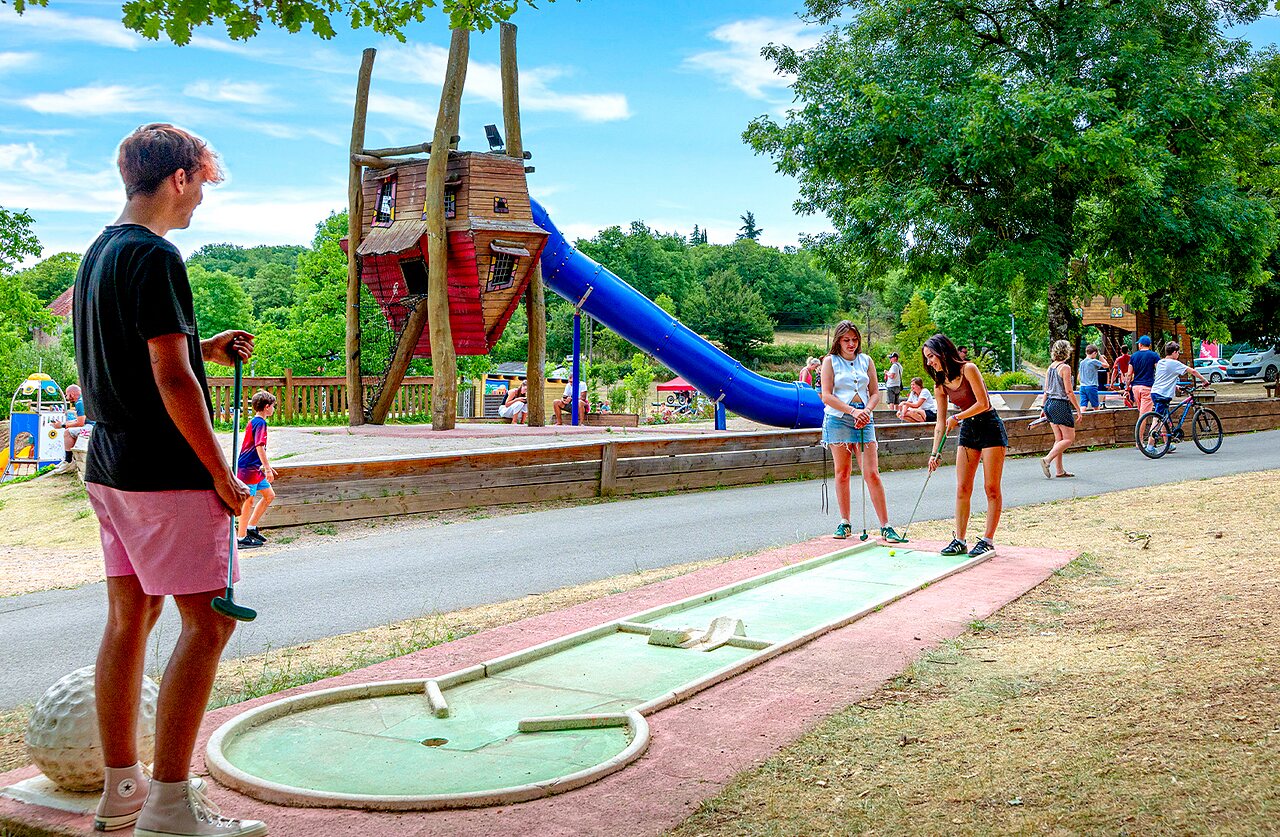 Family playing mini-golf and playground at CAPFUN Roca d'Amour campsite in PADIRAC (46).