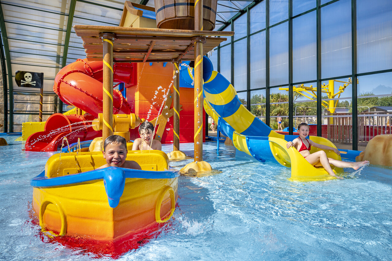 Children playing in covered water park with slides at CAPFUN La Route Blanche campsite in Breville sur Mer (50).