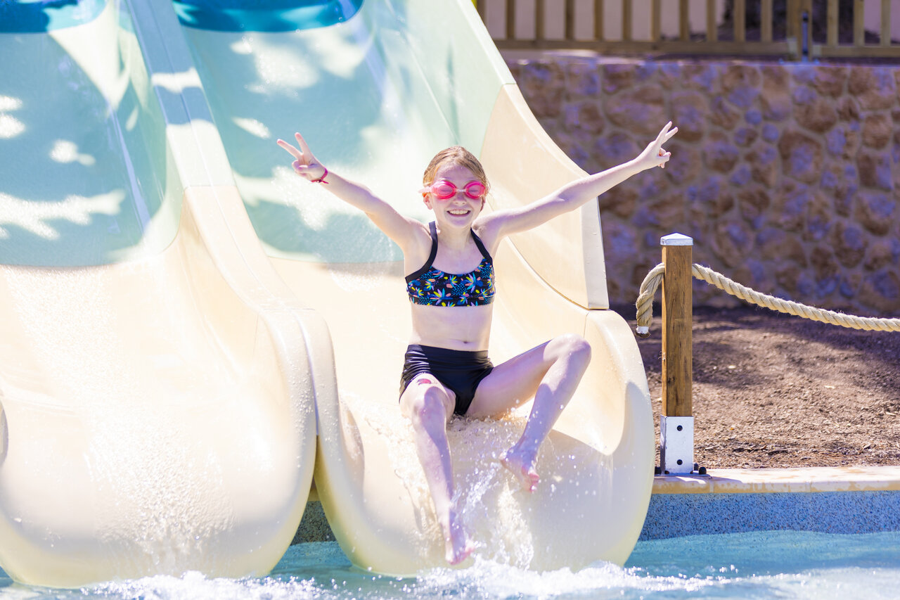 Smiling girl sliding down a water slide in the pool at CAPFUN La Rumba campsite in Fr�jus (83).