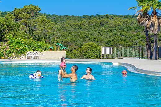Family with baby playing in outdoor swimming pool at CAPFUN La Rumba campsite in Fréjus (83).