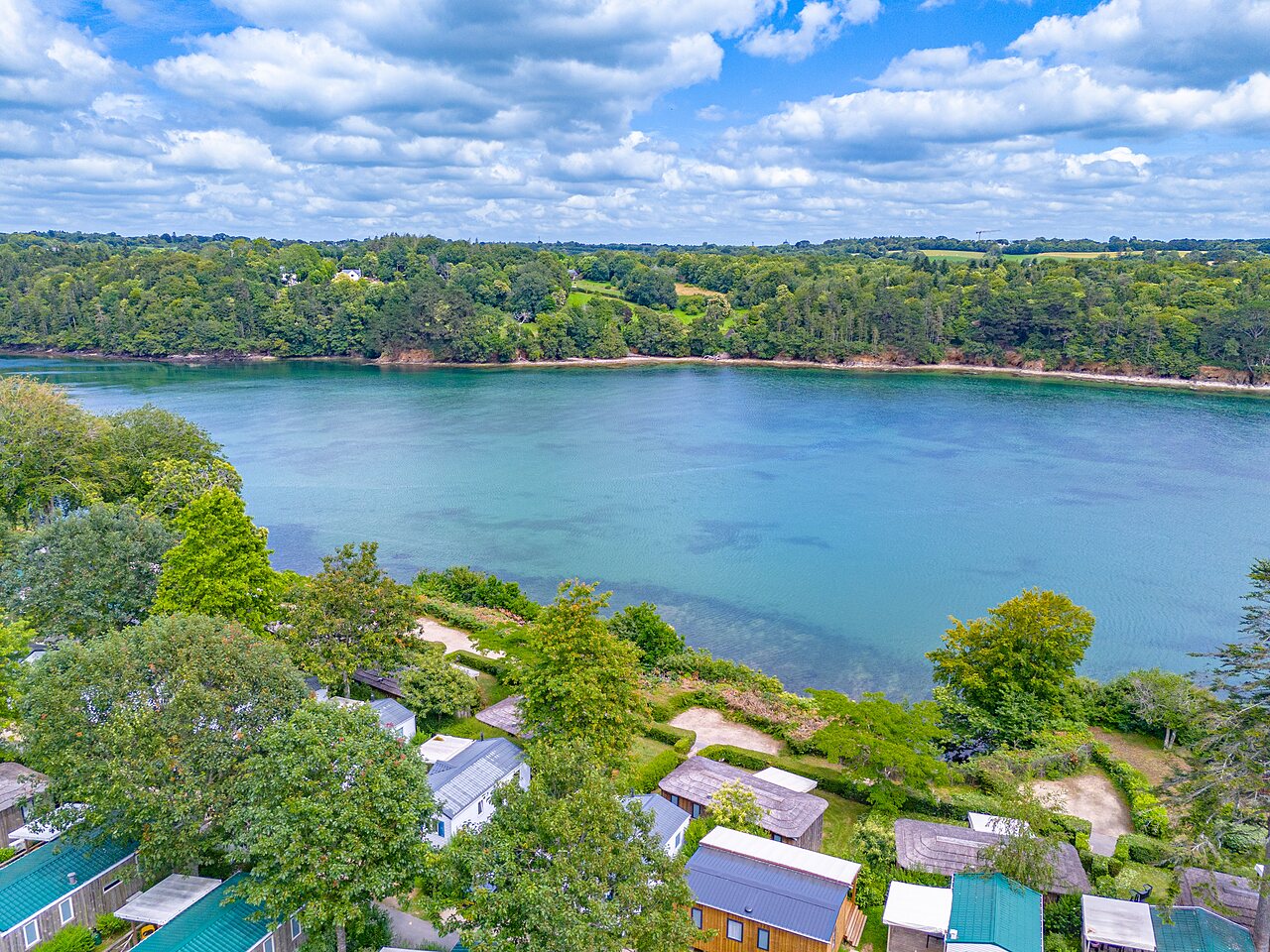 Mobile homes and body of water at CAPFUN Saint Laurent campsite in LA FORET FOUESNANT (29).