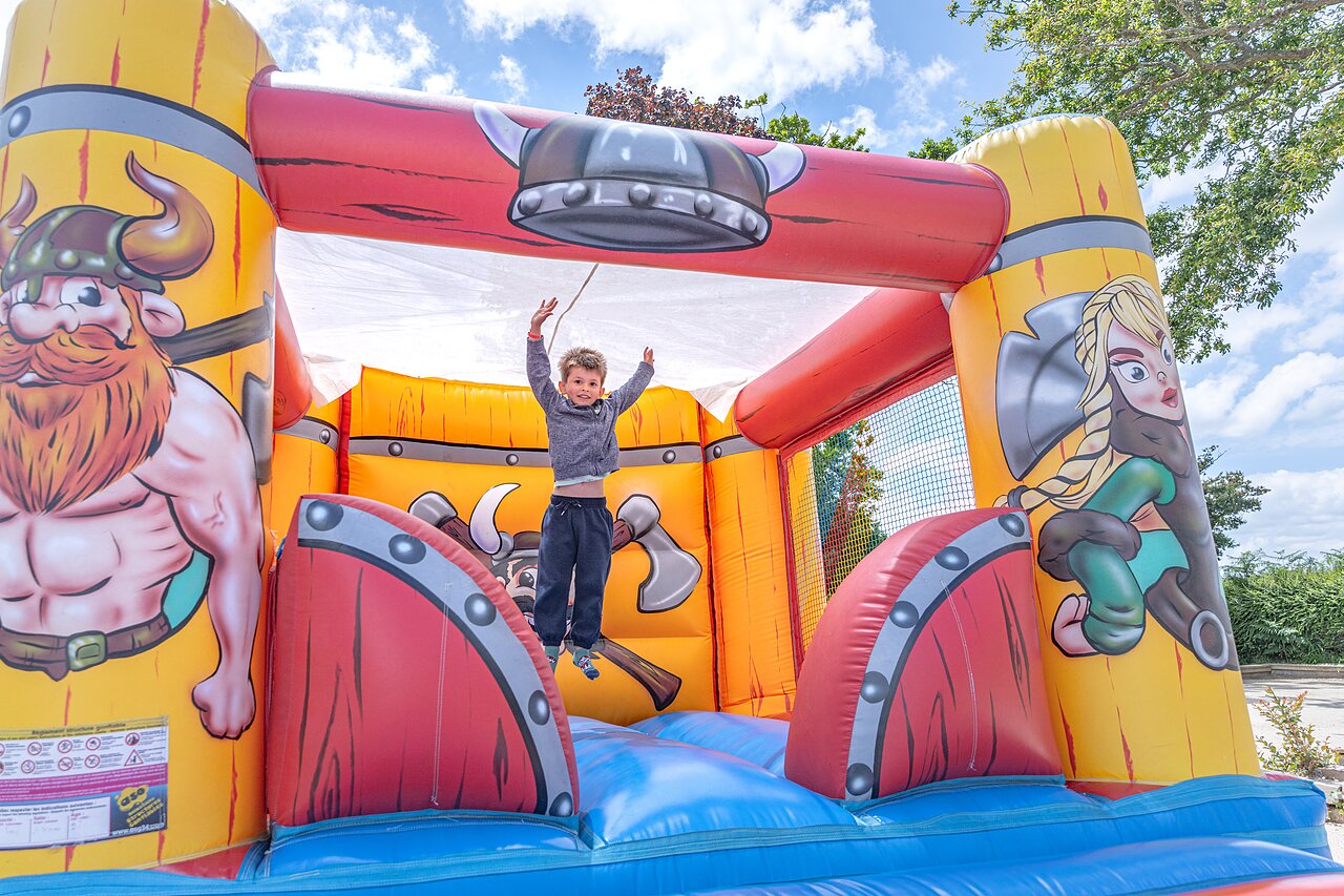 Viking inflatable castle, child jumping, at CAPFUN Saint Laurent campsite.